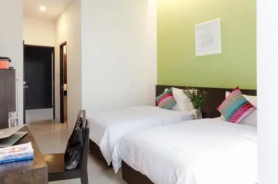a room with two beds and a table and a desk at @Home Residence in Bangkok