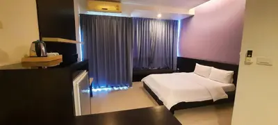 a bedroom with a bed and a window with purple curtains at @Home Residence in Bangkok