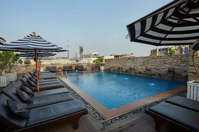 a swimming pool with a couch and an umbrella at Buddy Lodge, Khaosan Road in Bangkok
