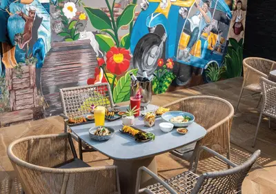 a table with food on it in front of a mural at Solitaire Bangkok Sukhumvit 11 in Bangkok