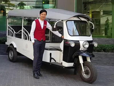 a man is standing next to a motor scooter at Solitaire Bangkok Sukhumvit 11 in Bangkok