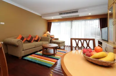 a living room with a couch and a table with a bowl of fruit at Admiral Suites Bangkok in Bangkok