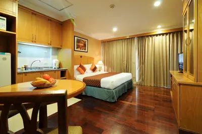 a hotel room with a bed and a table at Admiral Suites Bangkok in Bangkok
