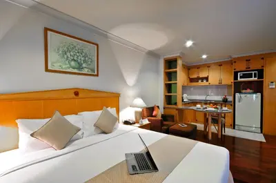 a bedroom with a bed with a laptop on it at Admiral Suites Bangkok in Bangkok