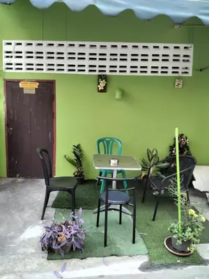 a table and chairs in front of a green wall at Danee Hostel in Bangkok
