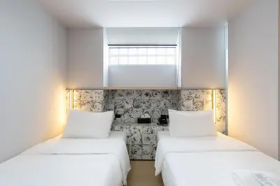 two beds in a room with white walls at Metz Pratunam in Bangkok