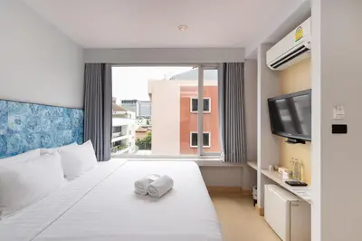 a bedroom with a white bed with a large window at Metz Pratunam in Bangkok