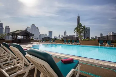 a swimming pool with lounge chairs and a city skyline at Ramada by Wyndham D MA Bangkok in Bangkok