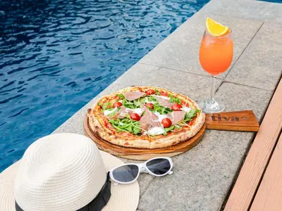 a pizza and a drink on a table next to a pool at Pullman Bangkok Hotel G in Bangkok