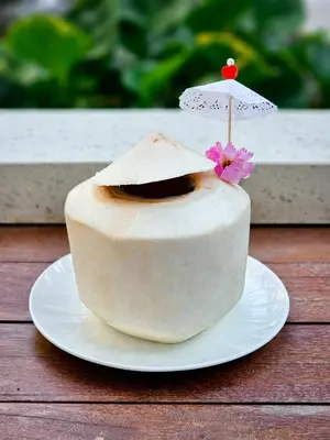 a cake on a plate with an umbrella on top at Feung Nakorn Balcony Rooms and Cafe in Bangkok