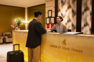 a man and a woman standing at a reception desk at lebua at State Tower in Bangkok