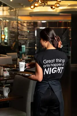 a woman standing at a table with a coffee cup at Night Hotel Bangkok - Sukhumvit 15 in Bangkok