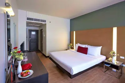 a bedroom with a large white bed and a table at Ambassador Hotel Bangkok in Bangkok