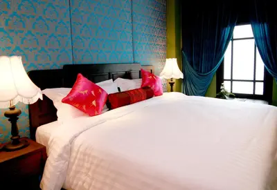 a bedroom with a large white bed with red pillows at Shanghai Mansion Bangkok in Bangkok
