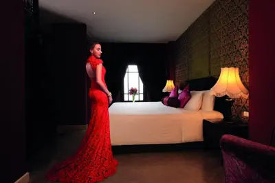 a woman in a red dress standing in front of a bed at Shanghai Mansion Bangkok in Bangkok