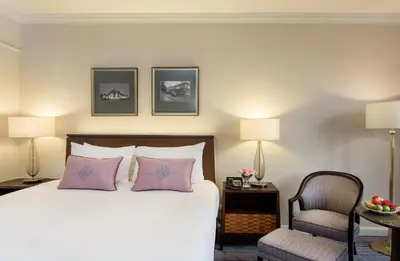 a bedroom with a bed with pink pillows and a chair at The Sukosol Hotel in Bangkok