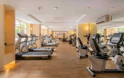 a gym with a row of treadmills and machines at The Sukosol Hotel in Bangkok