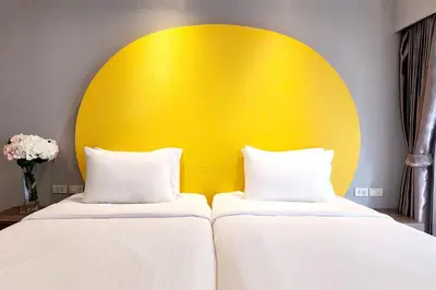 two beds in a room with a yellow headboard at FuramaXclusive Sukhumvit in Bangkok