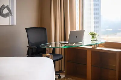 a glass table with a laptop on a desk with a chair at Centara Grand at Central Plaza Ladprao Bangkok in Bangkok