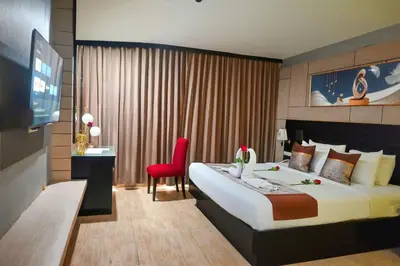 a hotel room with a large bed and a red chair at Boss Suites Nana Hotel in Bangkok