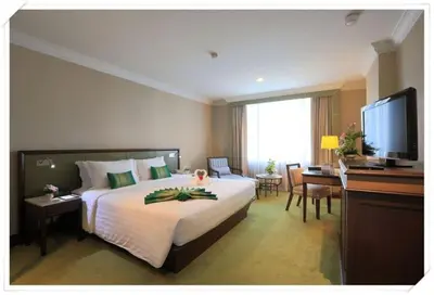 a hotel room with a bed and a desk and a television at Golden Tulip Sovereign Hotel Bangkok in Bangkok