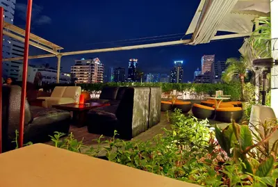 a rooftop patio with a view of the city at night at Le Fenix Sukhumvit 11 Bangkok in Bangkok