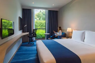 a woman sitting in a chair in a hotel room at Holiday Inn Express Bangkok Soi Soonvijai by IHG in Bangkok