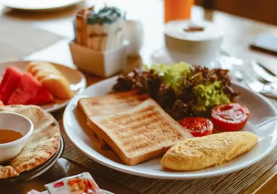 a white plate of food with bread and vegetables on a table at Fraser Suites Sukhumvit Bangkok in Bangkok
