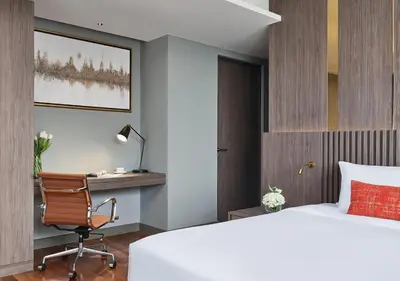 a bedroom with a bed and a desk and a chair at Fraser Suites Sukhumvit Bangkok in Bangkok