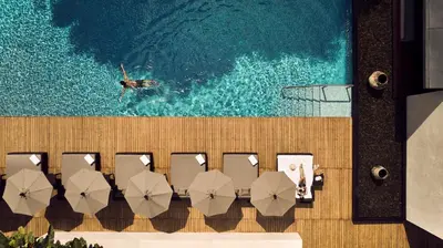 a pool with chairs and a swimmer in the water at COMO Metropolitan Bangkok in Bangkok