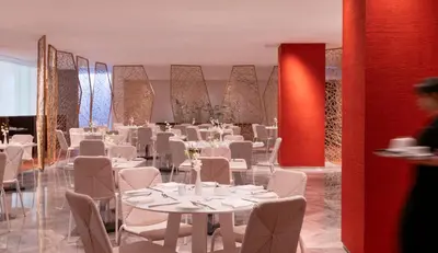 a dining room with white tables and white chairs at COMO Metropolitan Bangkok in Bangkok