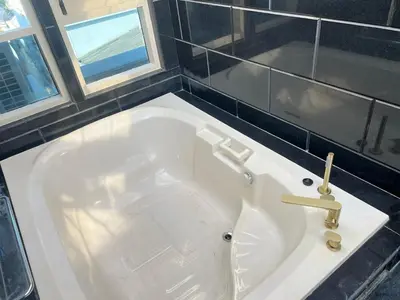 a large white tub in a bathroom with two windows at V20 Boutique Jacuzzi Hotel in Bangkok