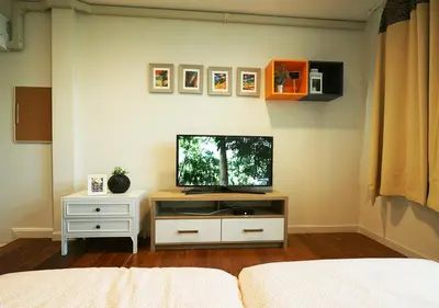 a living room with a tv on a white cabinet at The Serene House Bangkok in Bangkok