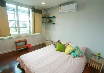 a bedroom with a white bed with pillows on it at The Serene House Bangkok in Bangkok
