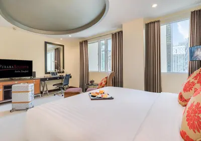 a hotel room with a white bed and a desk at FuramaXclusive Asoke, Bangkok in Bangkok