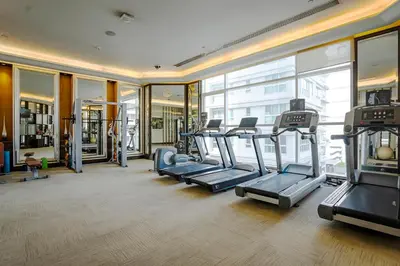 a gym with cardio equipment in a building with windows at Hilton Bangkok Grande Asoke in Bangkok
