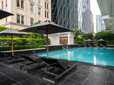a swimming pool with chairs and umbrellas in a city at Grande Centre Point Ploenchit in Bangkok