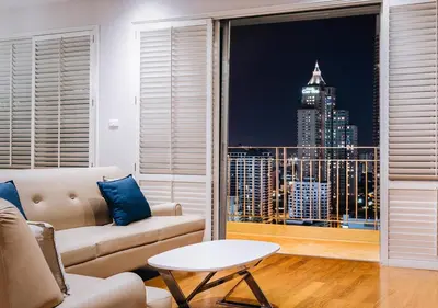 a living room with a couch and a view of a city at Grande Centre Point Ploenchit in Bangkok