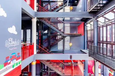 a spiral staircase in a building with red railing at CLOUD on Saladaeng Silom Hostel Bangkok in Bangkok