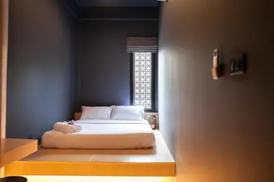 a small bedroom with a bed with a window at CLOUD on Saladaeng Silom Hostel Bangkok in Bangkok