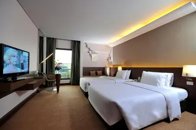 a hotel room with two beds and a flat screen tv at Rama Gardens Hotel Bangkok in Bangkok