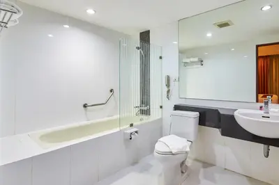 a bathroom with a sink and a toilet and a bath tub at Nana Hiso Hotel in Bangkok
