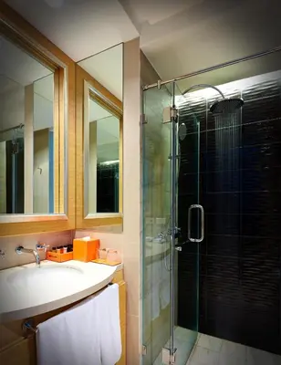 a bathroom with a sink and a glass shower at The Duchess Hotel in Bangkok