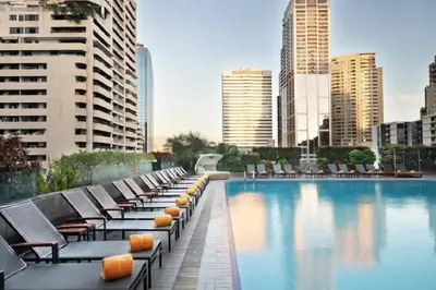 a hotel swimming pool with lounge chairs and buildings at Rembrandt Hotel Bangkok in Bangkok