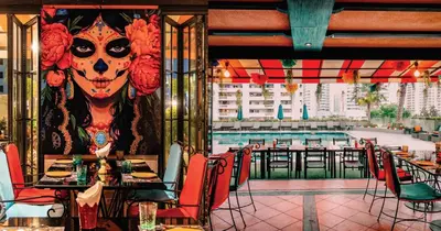 a restaurant with tables and chairs and a painting of a skull at Rembrandt Hotel Bangkok in Bangkok