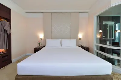 a large white bed in a bedroom with a window at Miracle Grand Convention Hotel in Bangkok