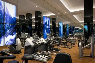 a gym with cardio machines and a large screen at The Sukhothai Bangkok in Bangkok