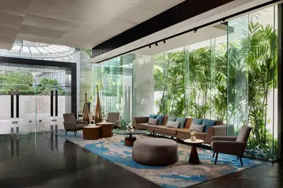 a lobby with couches and tables and glass walls at DoubleTree by Hilton Bangkok Ploenchit in Bangkok