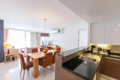 a kitchen and living room with a table and chairs at Oakwood Residence Sukhumvit 24 Bangkok in Bangkok