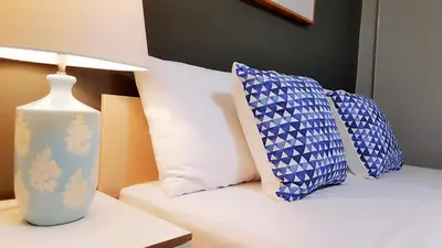 two pillows sitting on a bed next to a lamp at Baan Pinklao in Bangkok